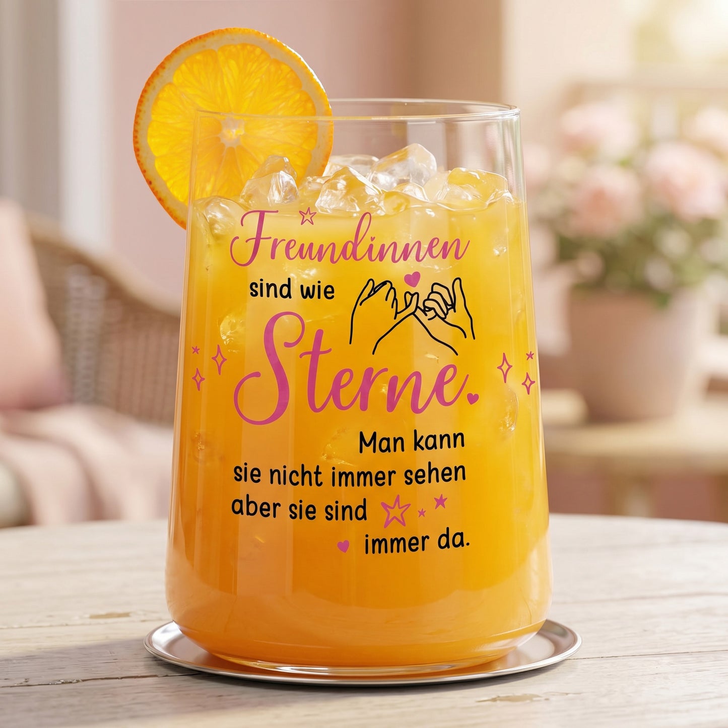Trinkglas mit Motiv „Freundinnen sind wie Sterne“ gefüllt mit orangem Getränk und Orangenscheibe auf hellem Tisch im wohnlichen Ambiente