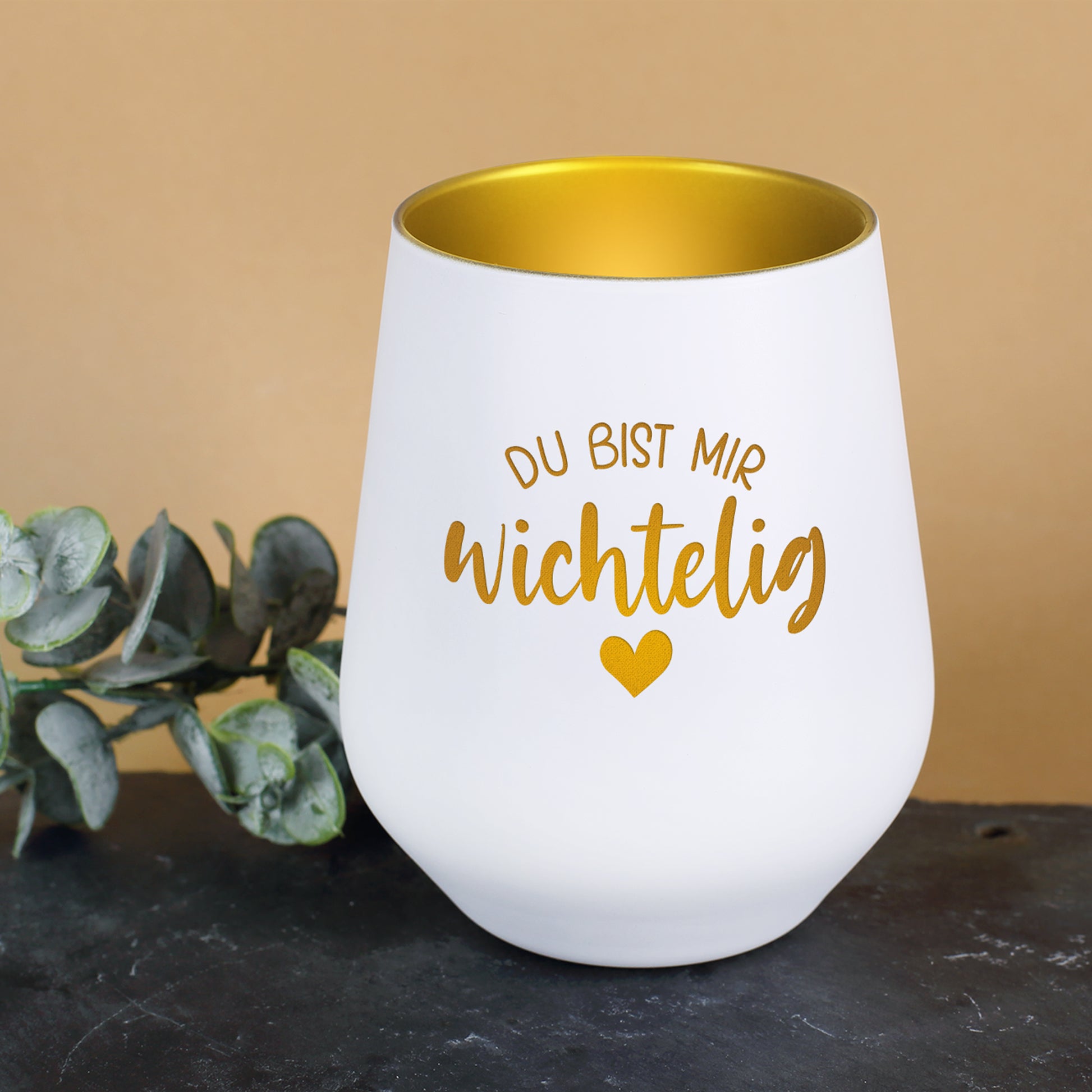 Weiß-goldenes Windlicht „Du bist mir wichtelig“ dekoriert mit grünen Zweigen