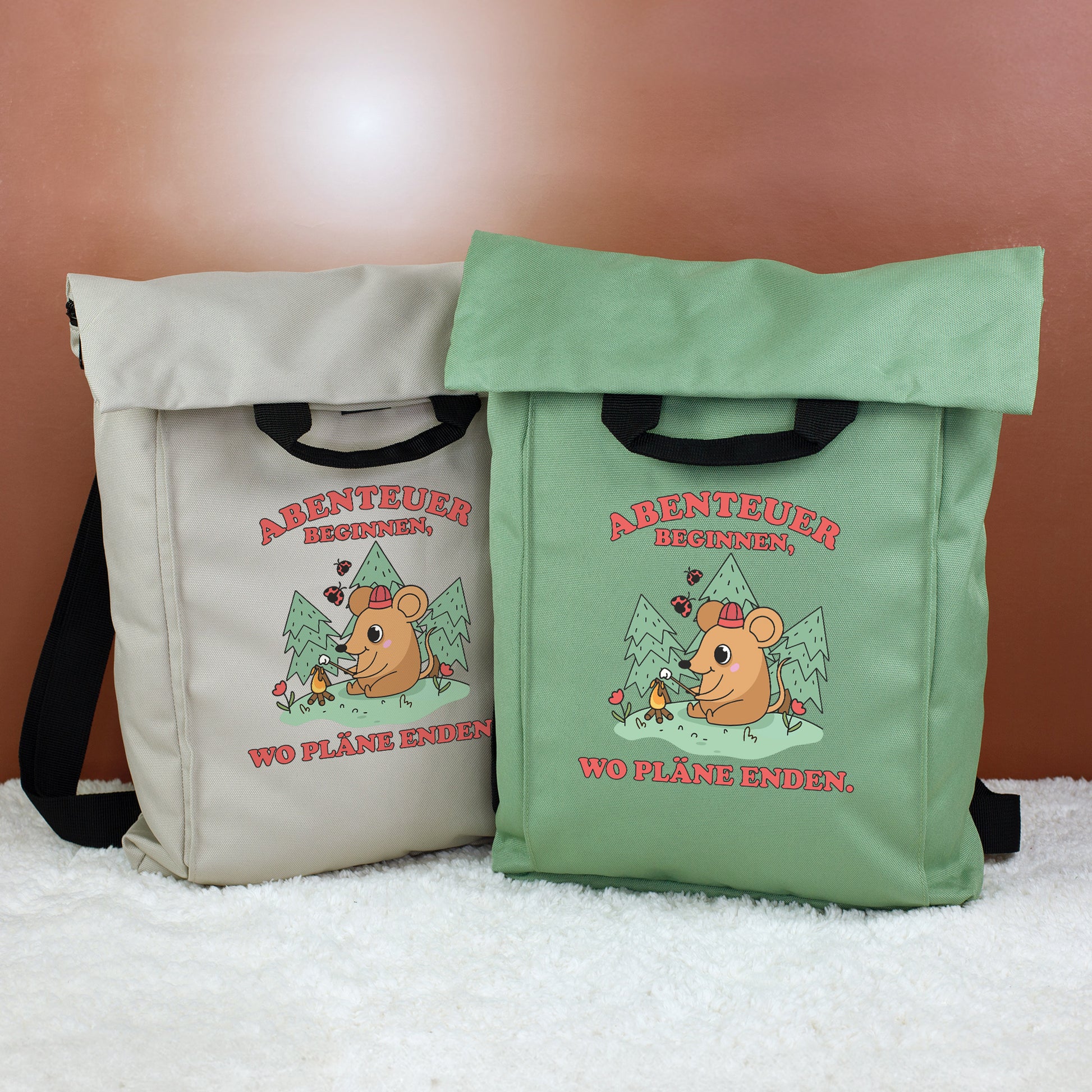 Zwei 2-in-1 Rucksäcke in Beige und Jadegrün mit Abenteuer-Maus Motiv und Spruch „Abenteuer beginnen, wo Pläne enden.“
