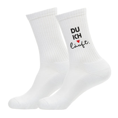 Produktfoto von zwei weißen Socken freigestellt auf weißem Hintergrund, Motiv „DU ICH läuft.“ mit Herz
