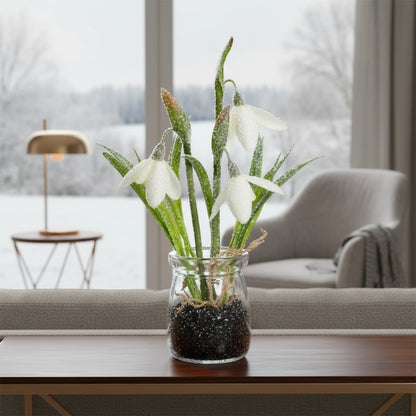 Kunst-Schneeglöckchen im Glas mit Eiskristall-Effekt als winterliche Tischdekoration auf einem Beistelltisch im Wohnzimmer