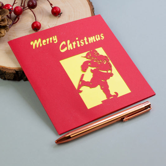 Rote Weihnachtskarte mit gelbem Innenfeld und „Merry Christmas“-Schriftzug, Motiv Weihnachtsmann auf Schlittschuhen.