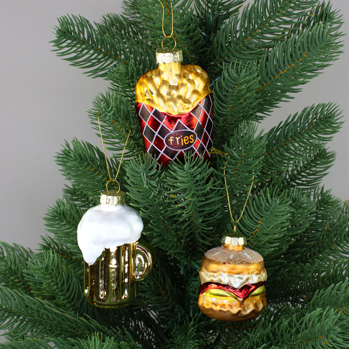 Burger, Bier und Pommes Glas-Baumschmuck gemeinsam dekoriert an einem grünen Weihnachtsbaum