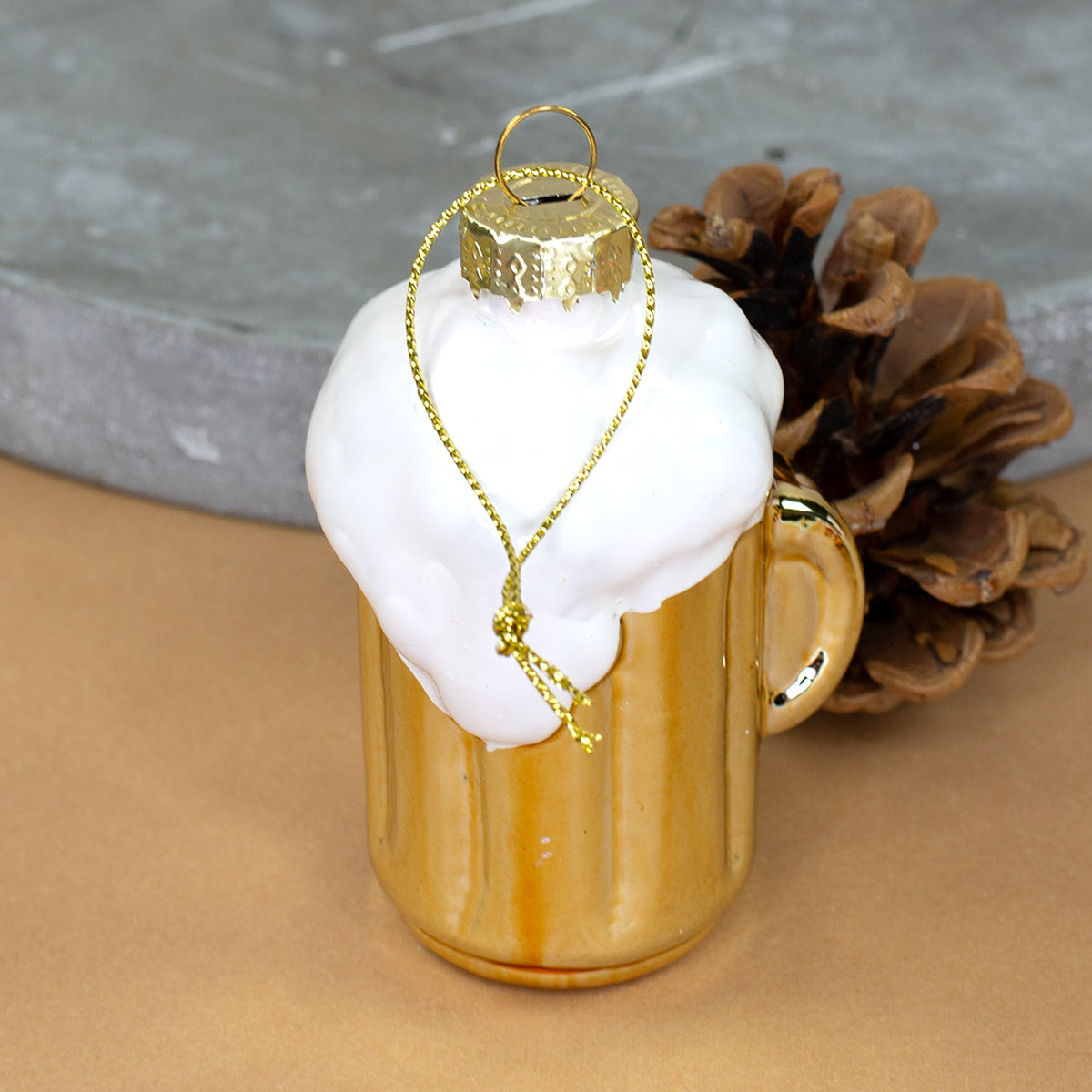 Goldfarbener Bierkrug aus Glas mit weißem Schaum und goldener Aufhängung von hinten