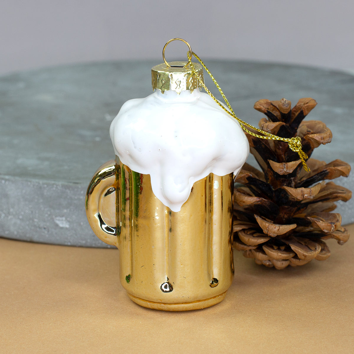 Goldfarbener Bierkrug aus Glas mit weißem Schaum als ausgefallener Weihnachtsbaumschmuck