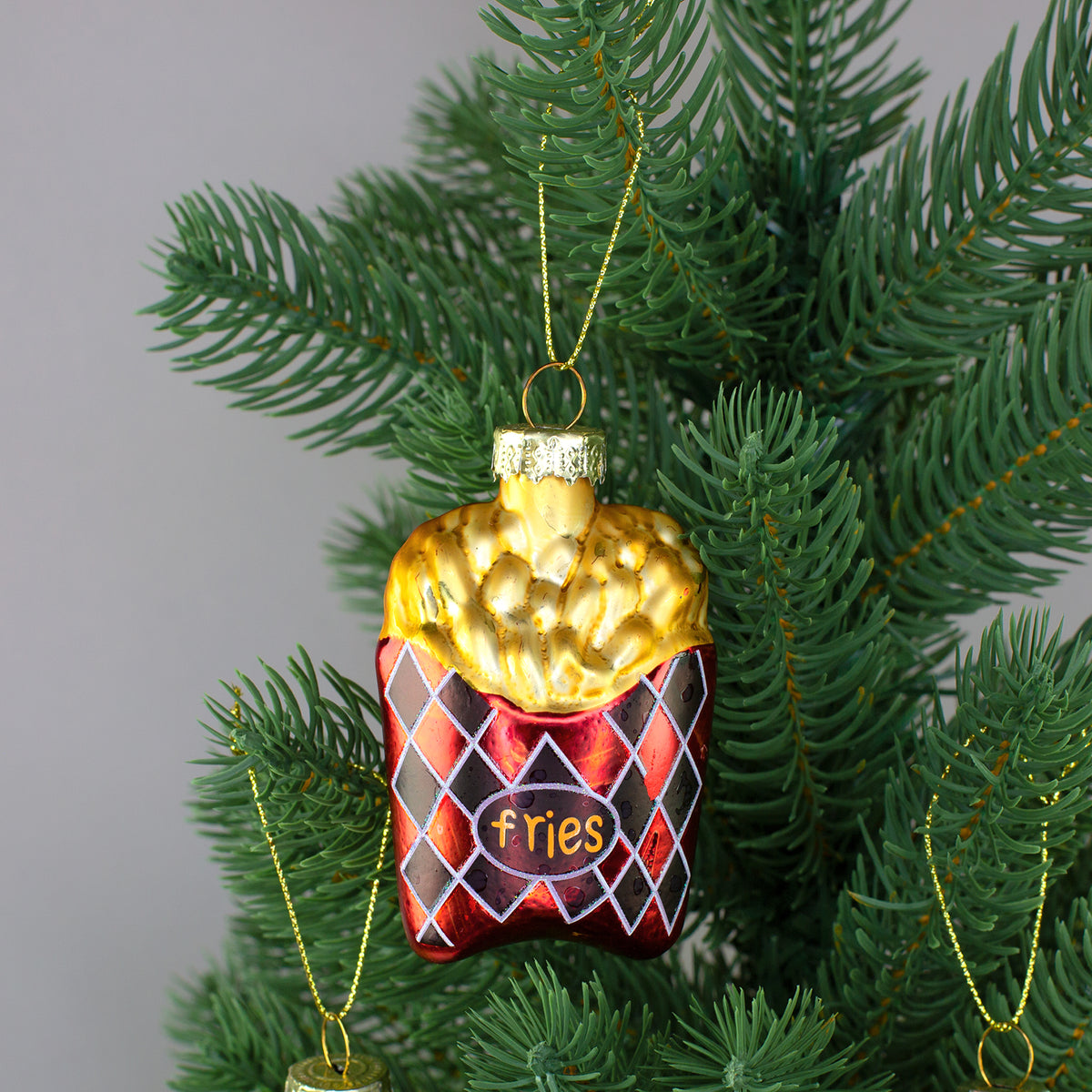 Pommes Glasanhänger in roter Verpackung mit Schriftzug fries am Weihnachtsbaum
