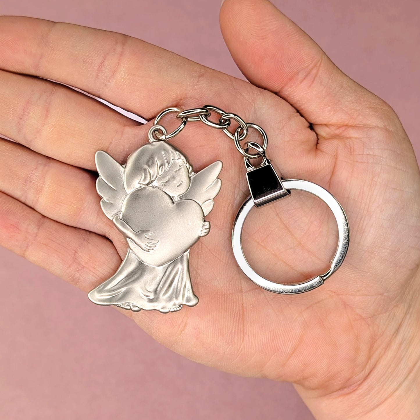 Schlüsselanhänger mit Schutzengel-Motiv in der Hand gehalten zur Größenveranschaulichung