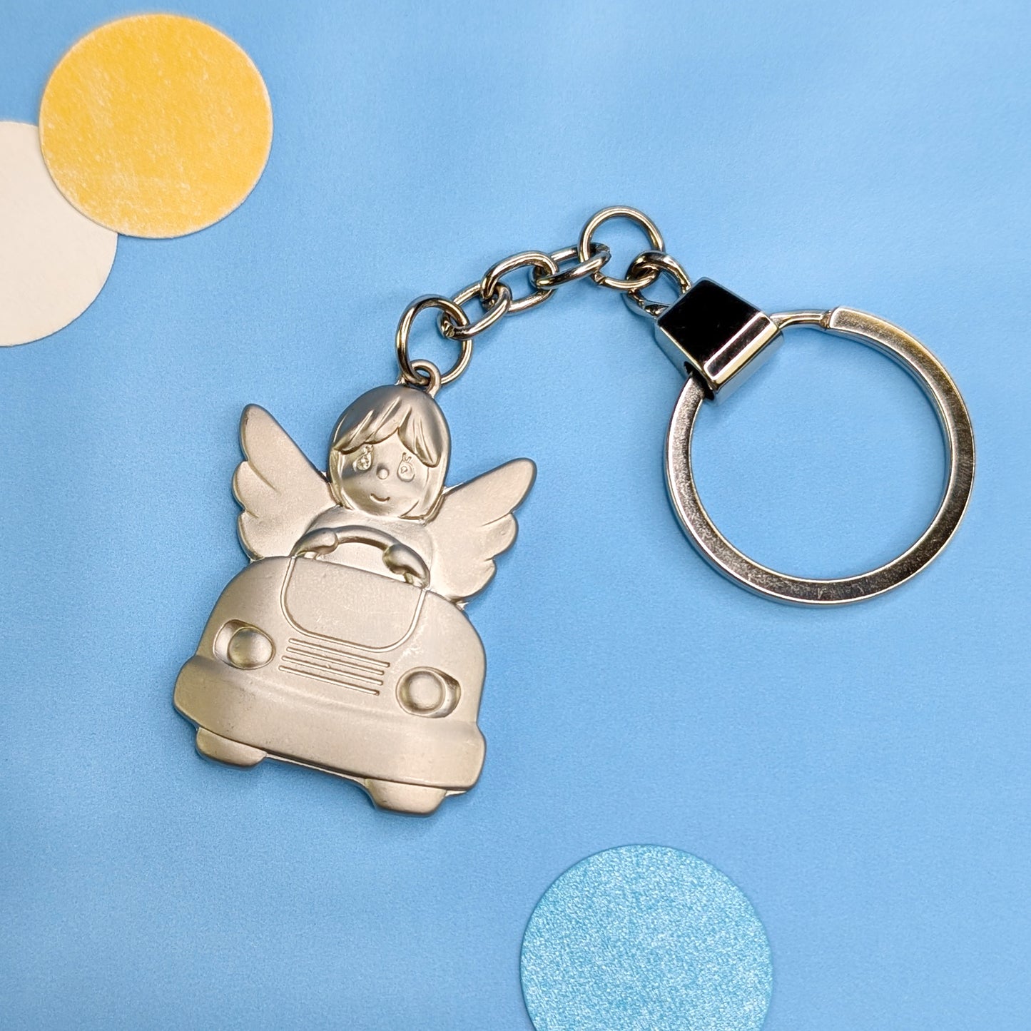 Schutzengel-Schlüsselanhänger im Auto – frontal fotografiert auf blauem Hintergrund