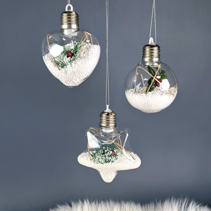 Drei beleuchtete Christbaumkugeln mit Styroporkugeln, Zweigen und roten Beeren vor grauem Hintergrund.