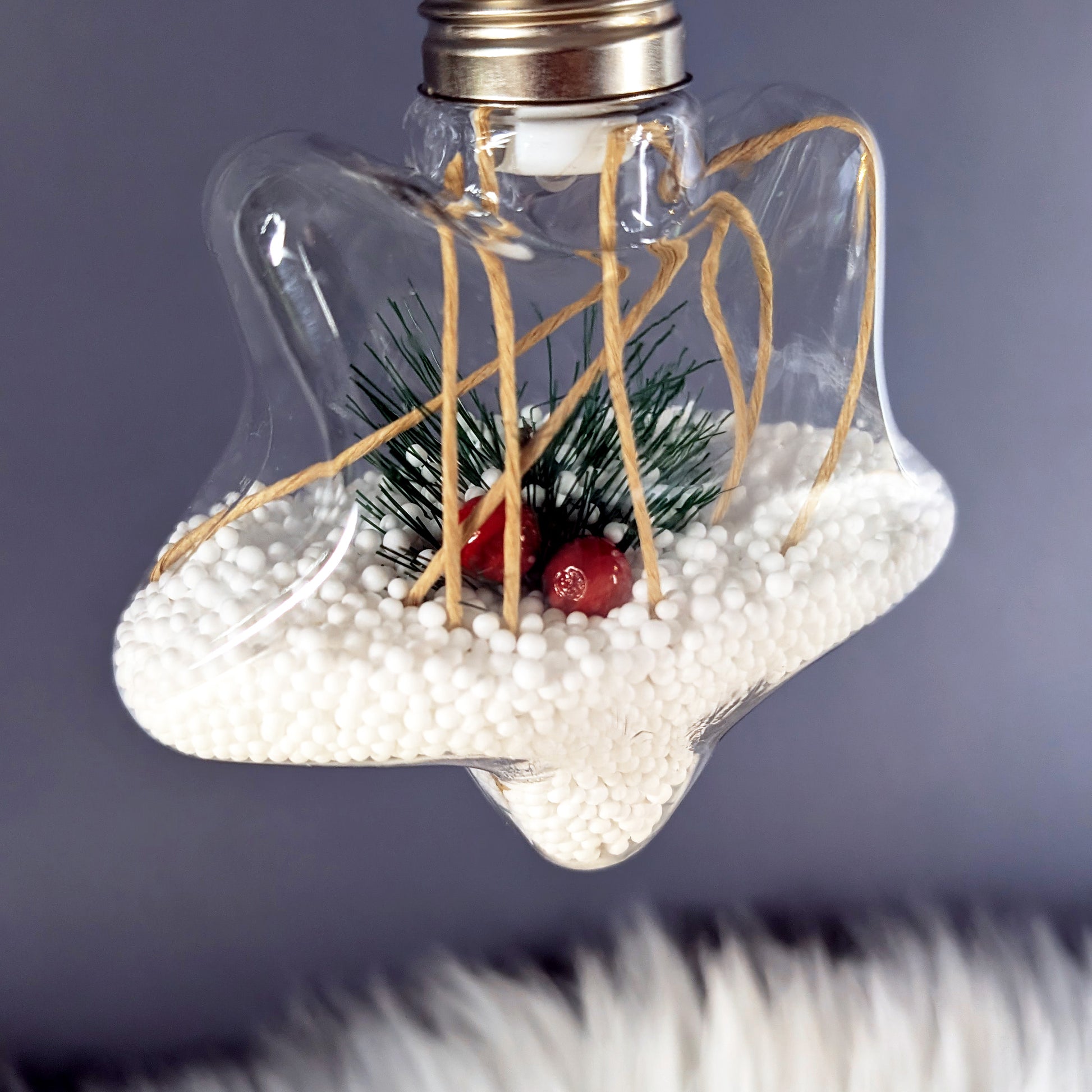 Sternförmige LED-Weihnachtskugel mit Tannenzweig, roten Beeren und warmem Licht.