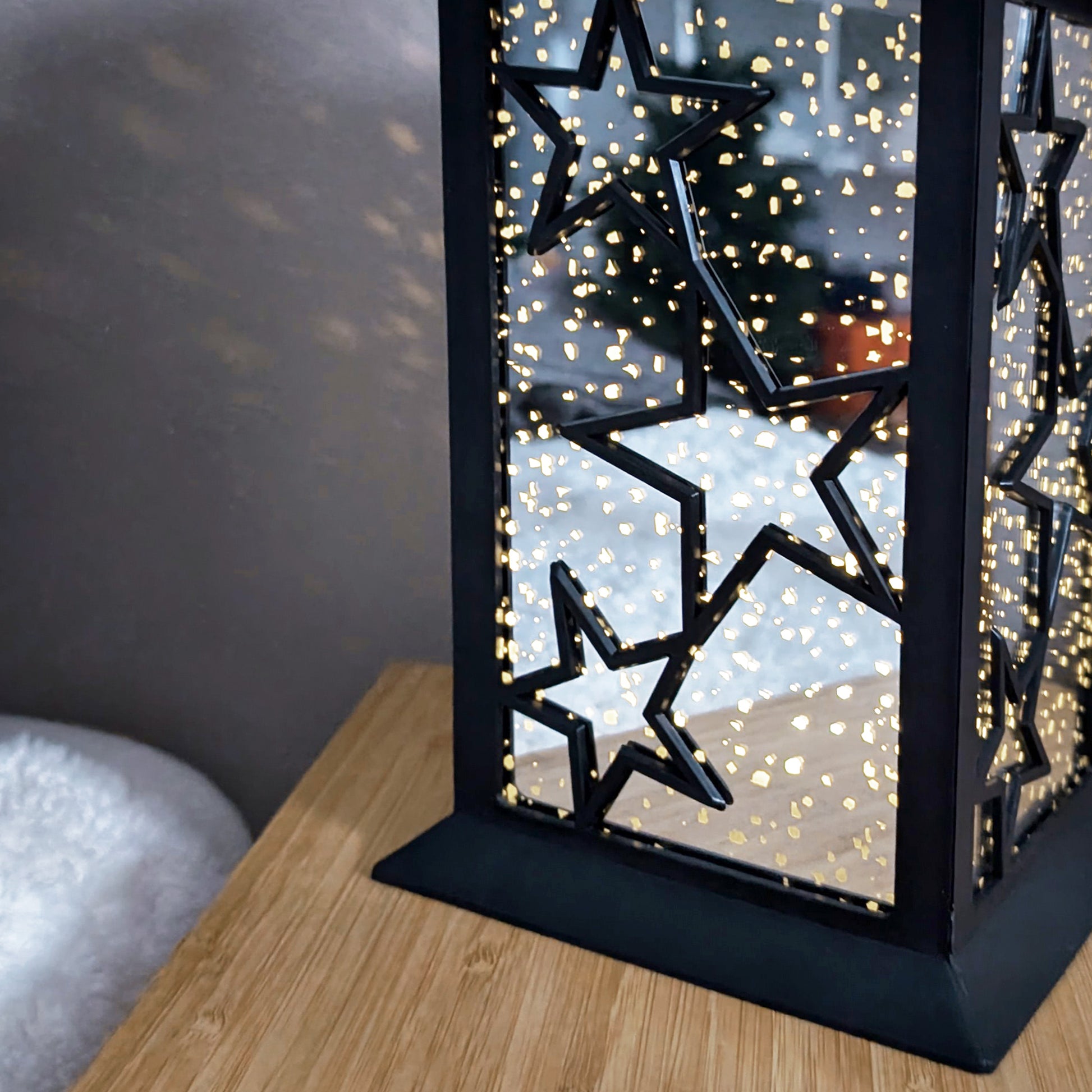 Detailaufnahme der leuchtenden LED-Laterne mit Sternenlichtspiel auf Holztisch