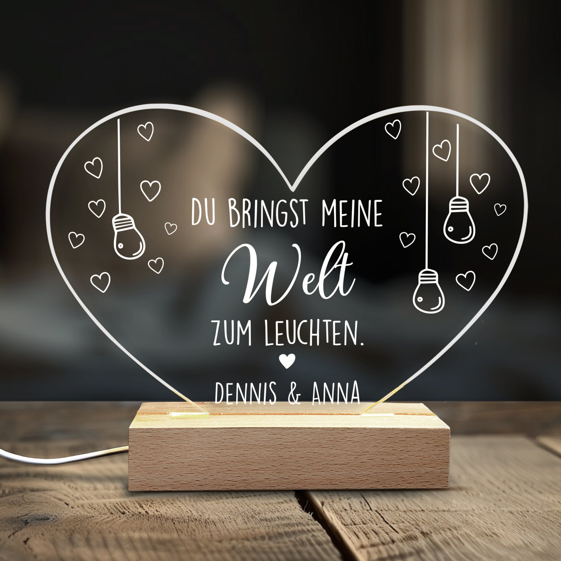 Acryl-Herzlampe mit Liebesspruch und Namen „Dennis & Anna“ auf Holzsockel, dekoriert auf Holztisch im Wohnzimmer
