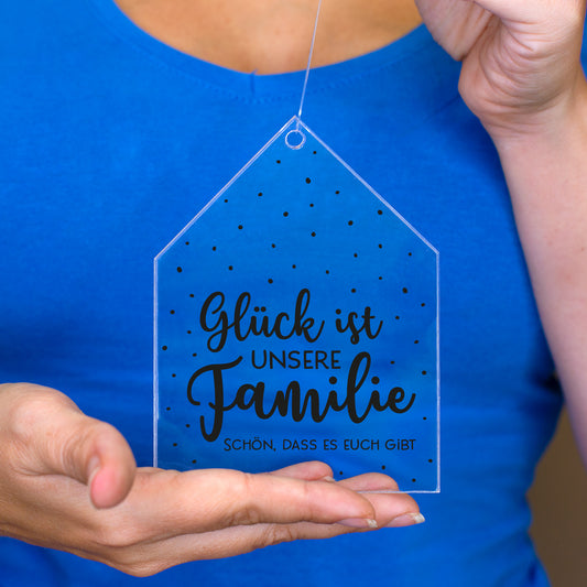 Personalisierter Acrylanhänger Glück ist unsere Familie wird vor blauem Shirt in den Händen gehalten