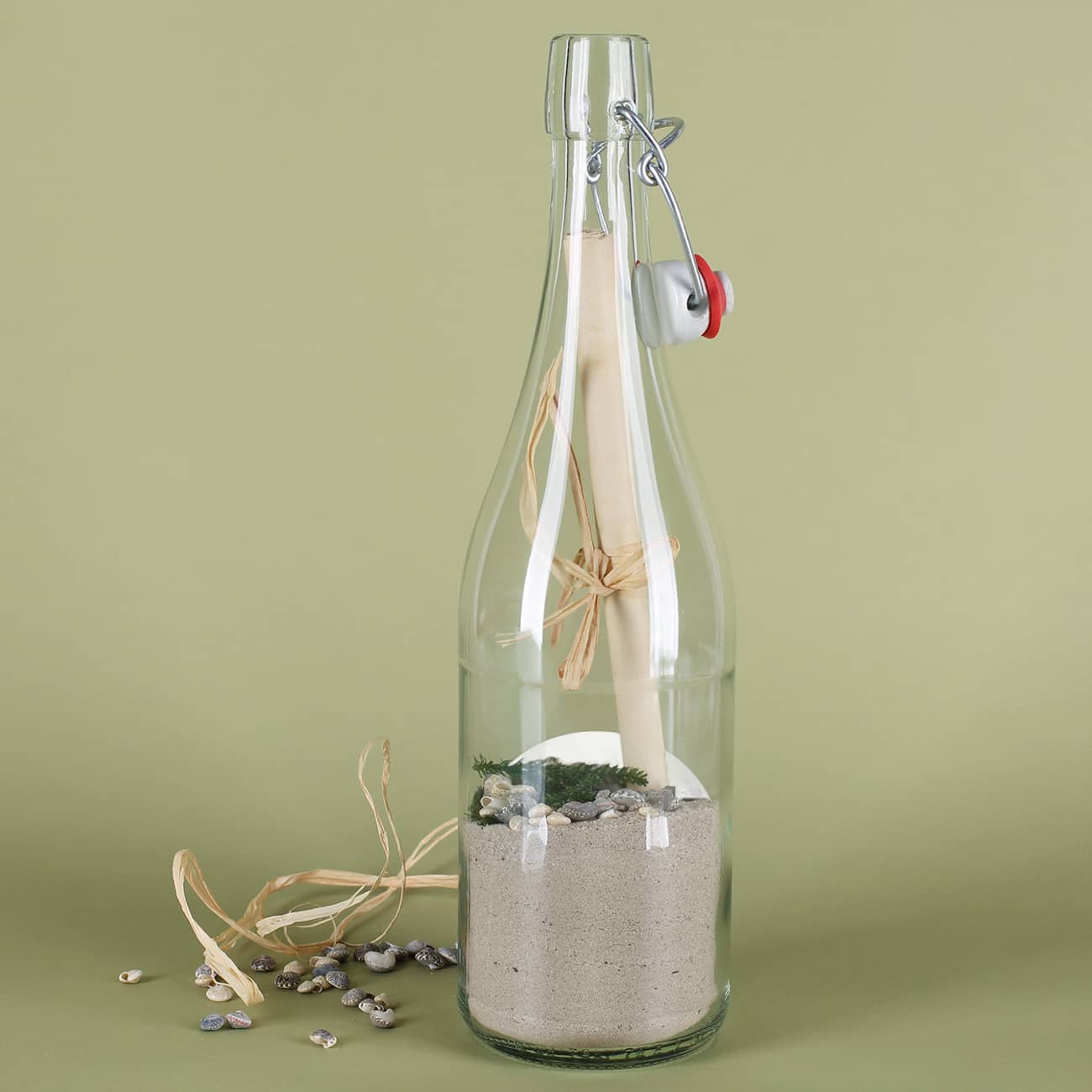 Gefüllte Flaschenpost mit Sand, Muscheln, Grün und Papier von hinten