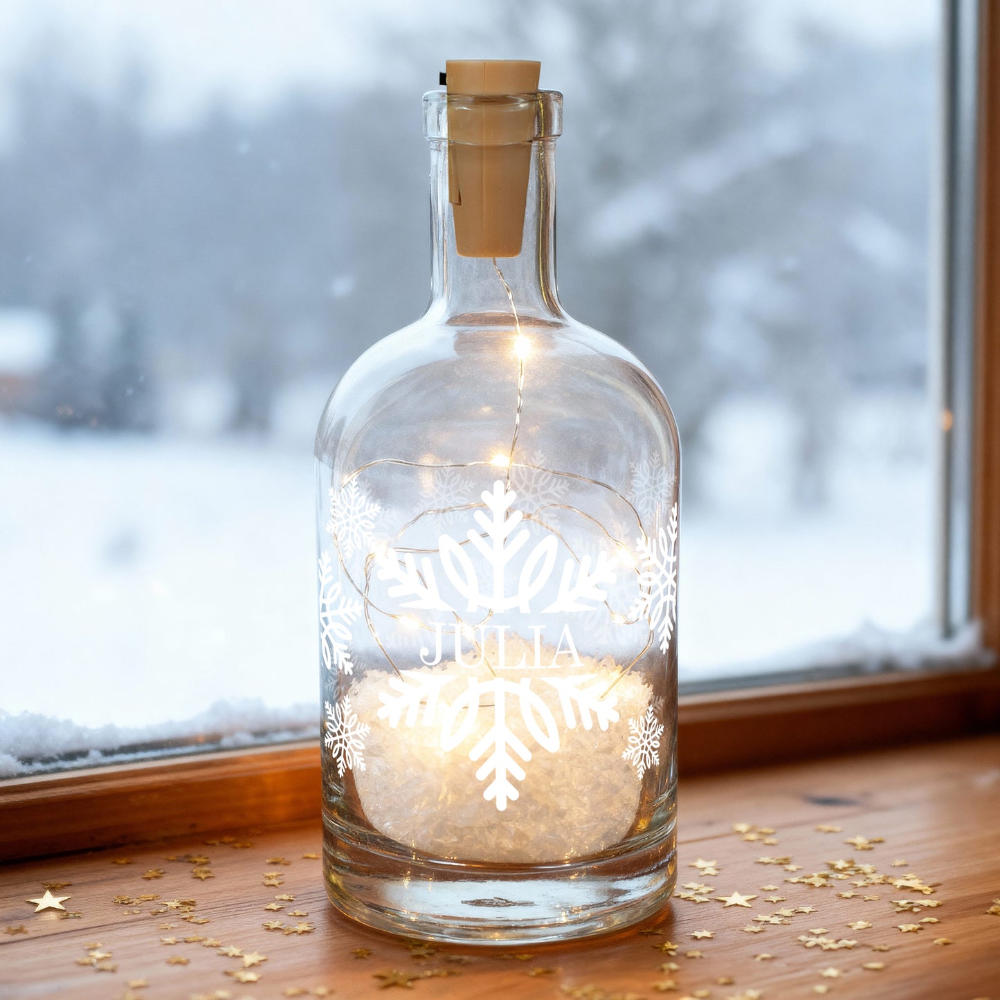 Beleuchtete Glasflasche mit Schneeflocken-Design und Name „Julia“ auf Fensterbank im Winter.