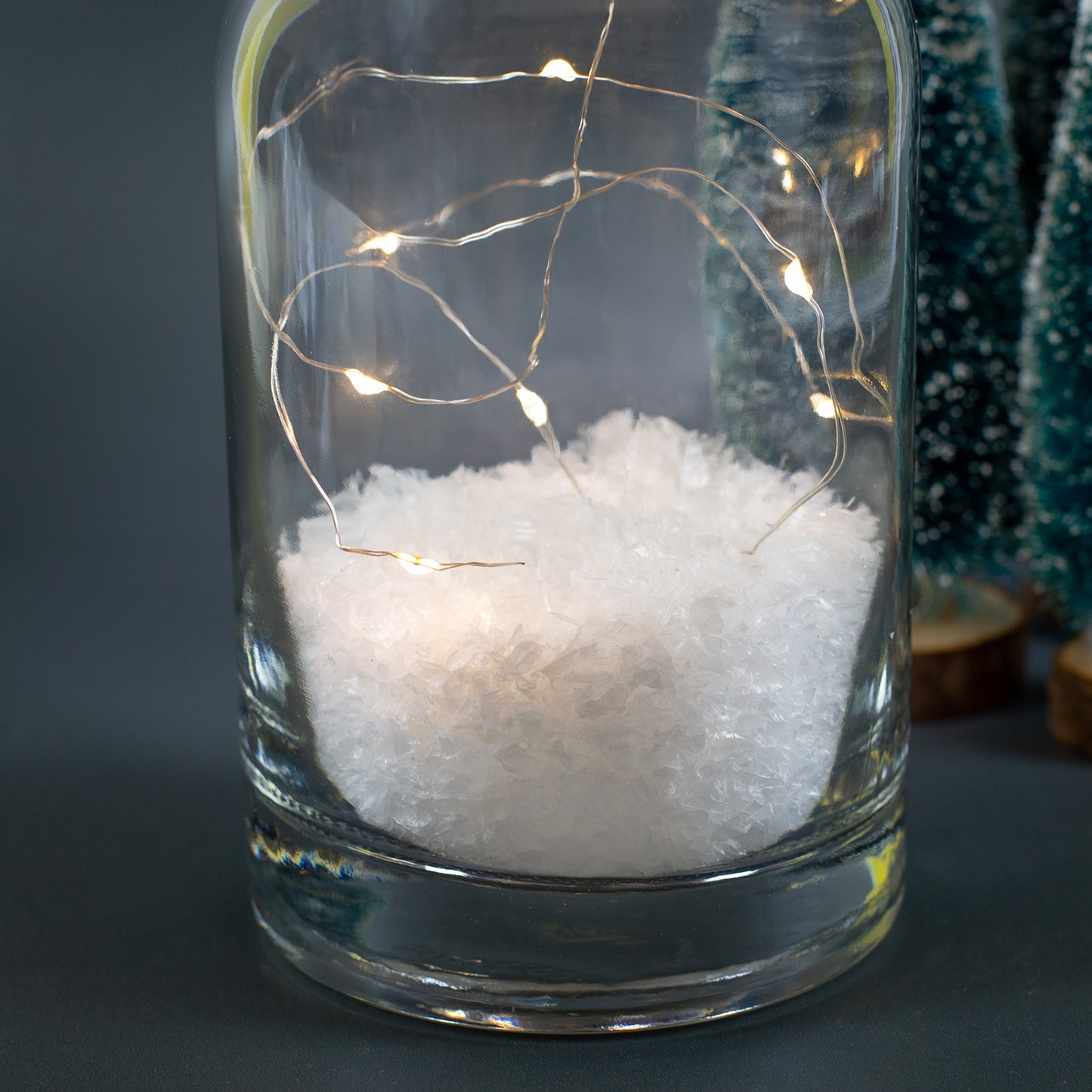 Detailaufnahme der Karaffe mit Kunstschnee und LED-Microlichtern im Inneren vor dunklem Hintergrund.