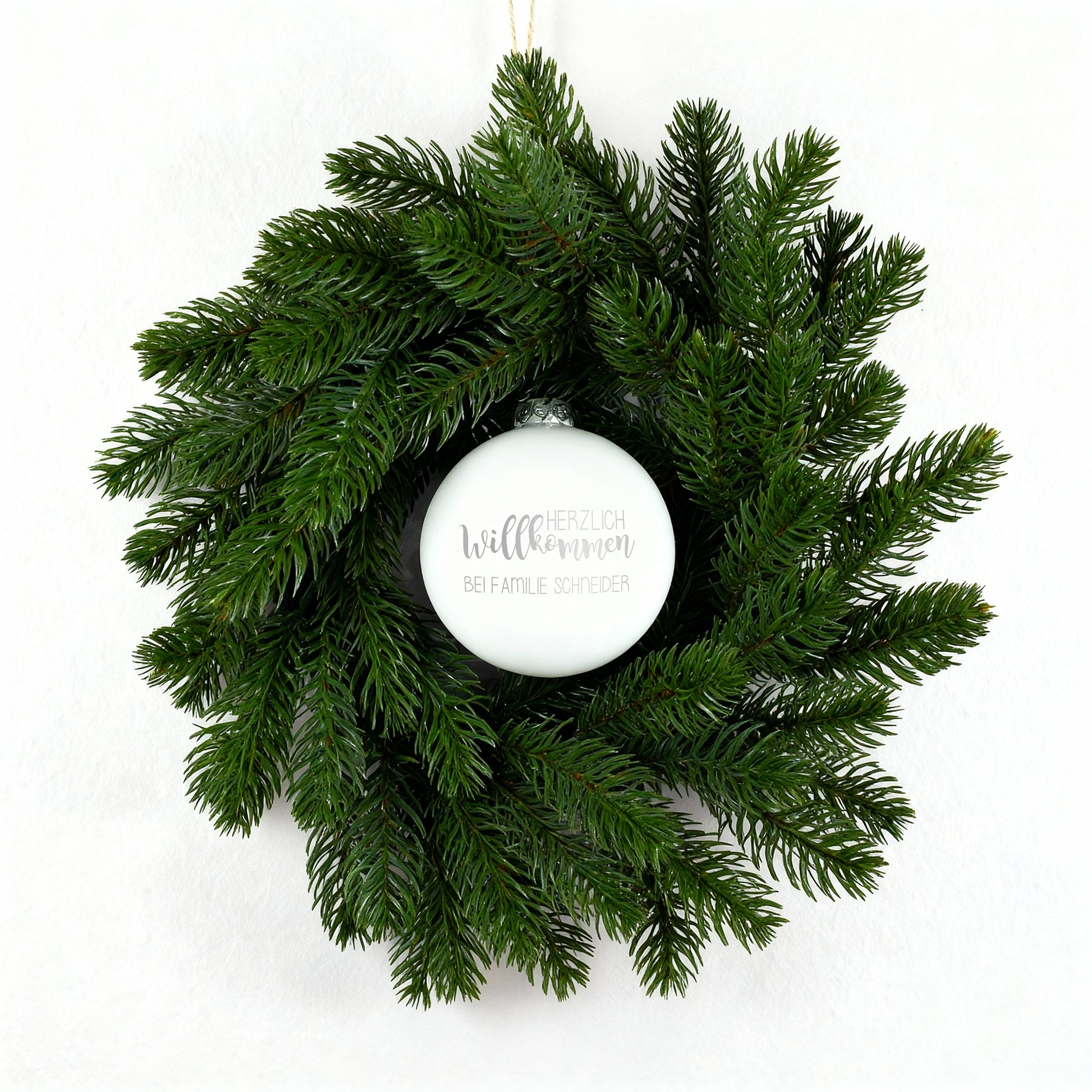 Weihnachts-Türkranz mit weißer gravierter Kugel „Herzlich willkommen“ auf weißem Hintergrund