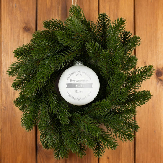 Türkranz aus Tannenzweigen mit weißer personalisierter Weihnachtskugel auf Holz
