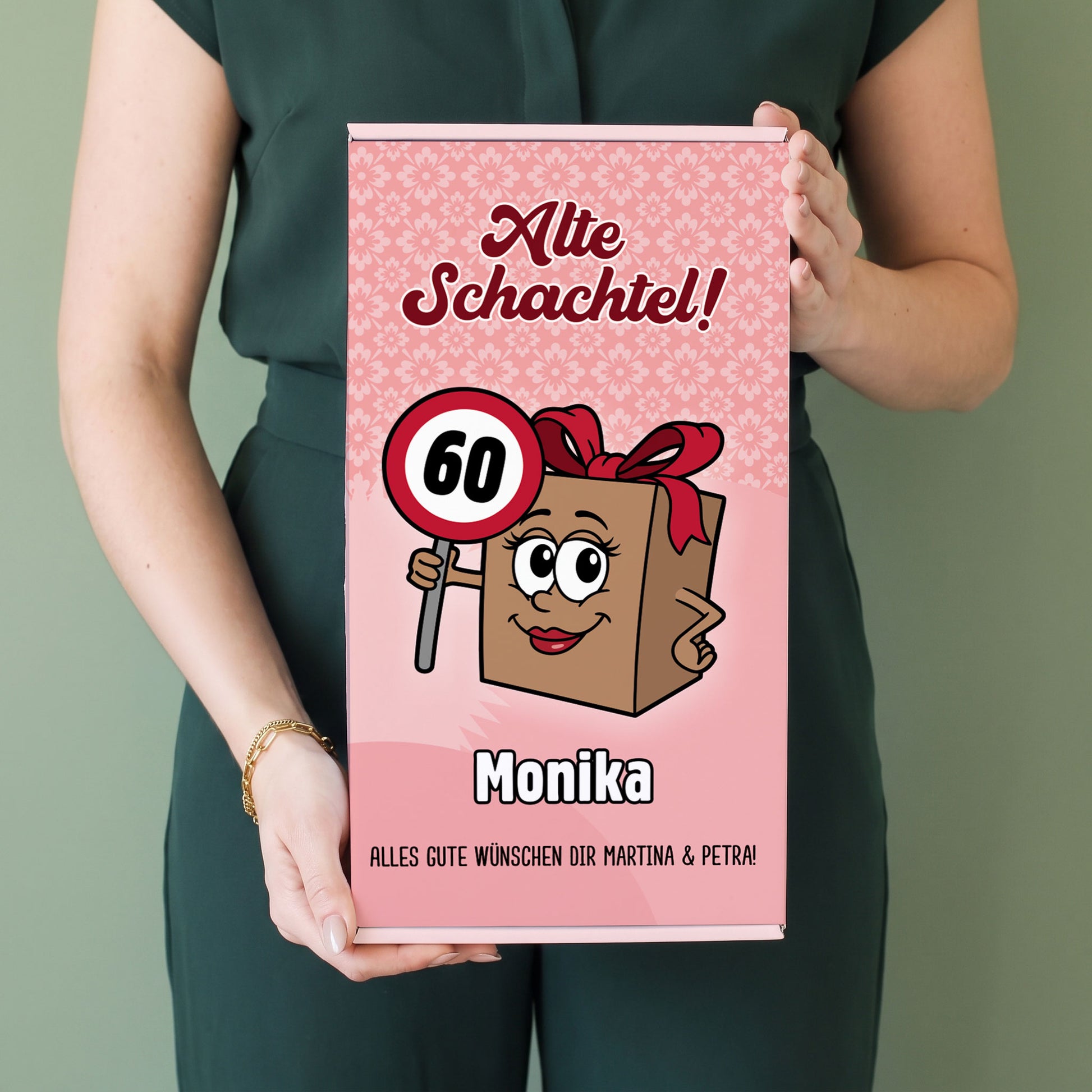 Frau hält personalisierte Geschenkbox „Alte Schachtel!“ mit Name Monika und Alter 60 in den Händen