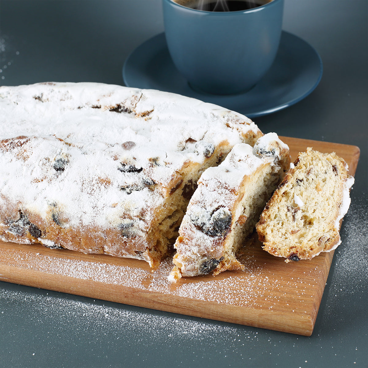 1. Angeschnittener Rosinenstollen mit Puderzucker, Rosinen und Nüssen auf einem Holzbrett