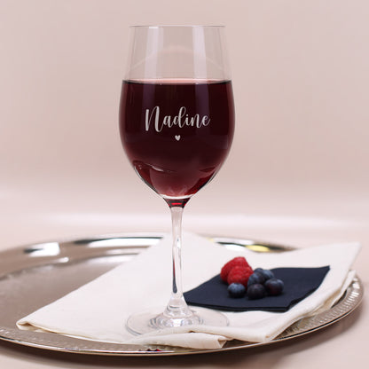 Graviertes Weinglas mit Name „Nadine“ und Herzsymbol, gefüllt mit Rotwein auf Tablett