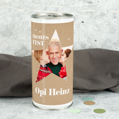 Weihnachtsbierdose mit großem Stern-Ausschnitt und eingedrucktem Familienfoto sowie Name „Opi Heinz“, winterliche Deko im Hintergrund.