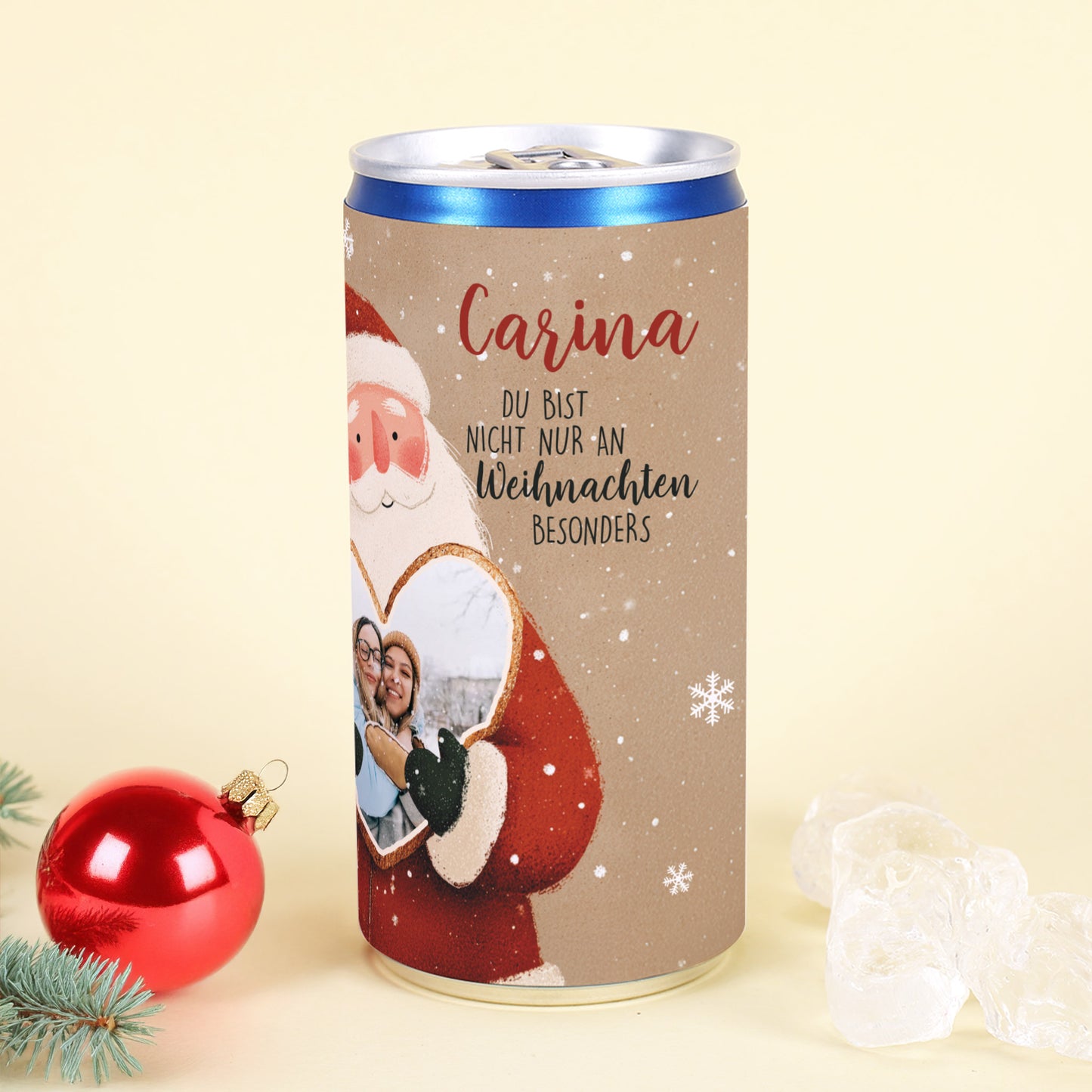 Personalisierte Secco-Dose mit Name „Carina“, Weihnachtsmann hält Herz mit Foto, dekoriert mit roter Kugel und Eisstücken.