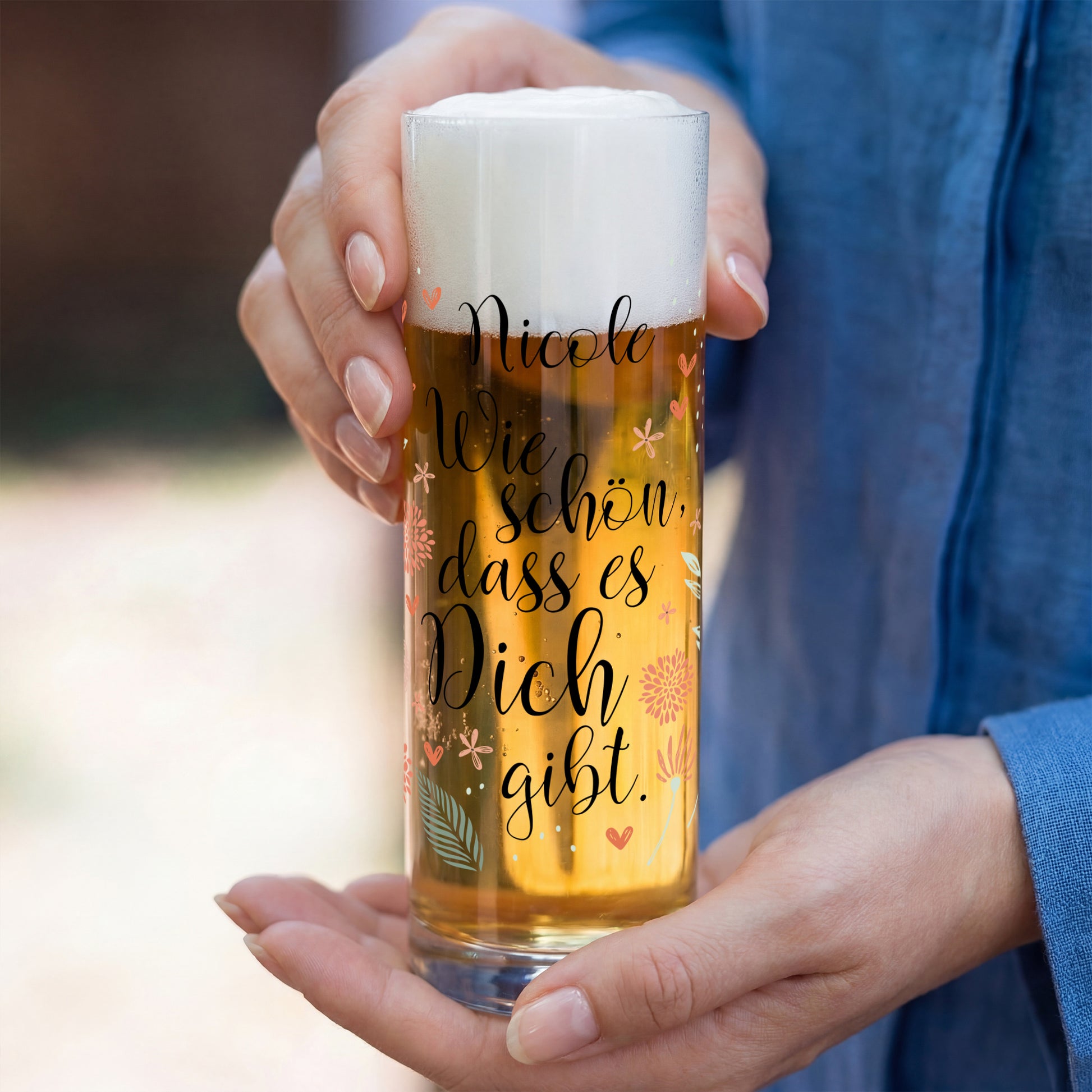 Bier Glas mit Name Nicole und Spruch Wie schön dass es Dich gibt, gehalten in zwei Händen