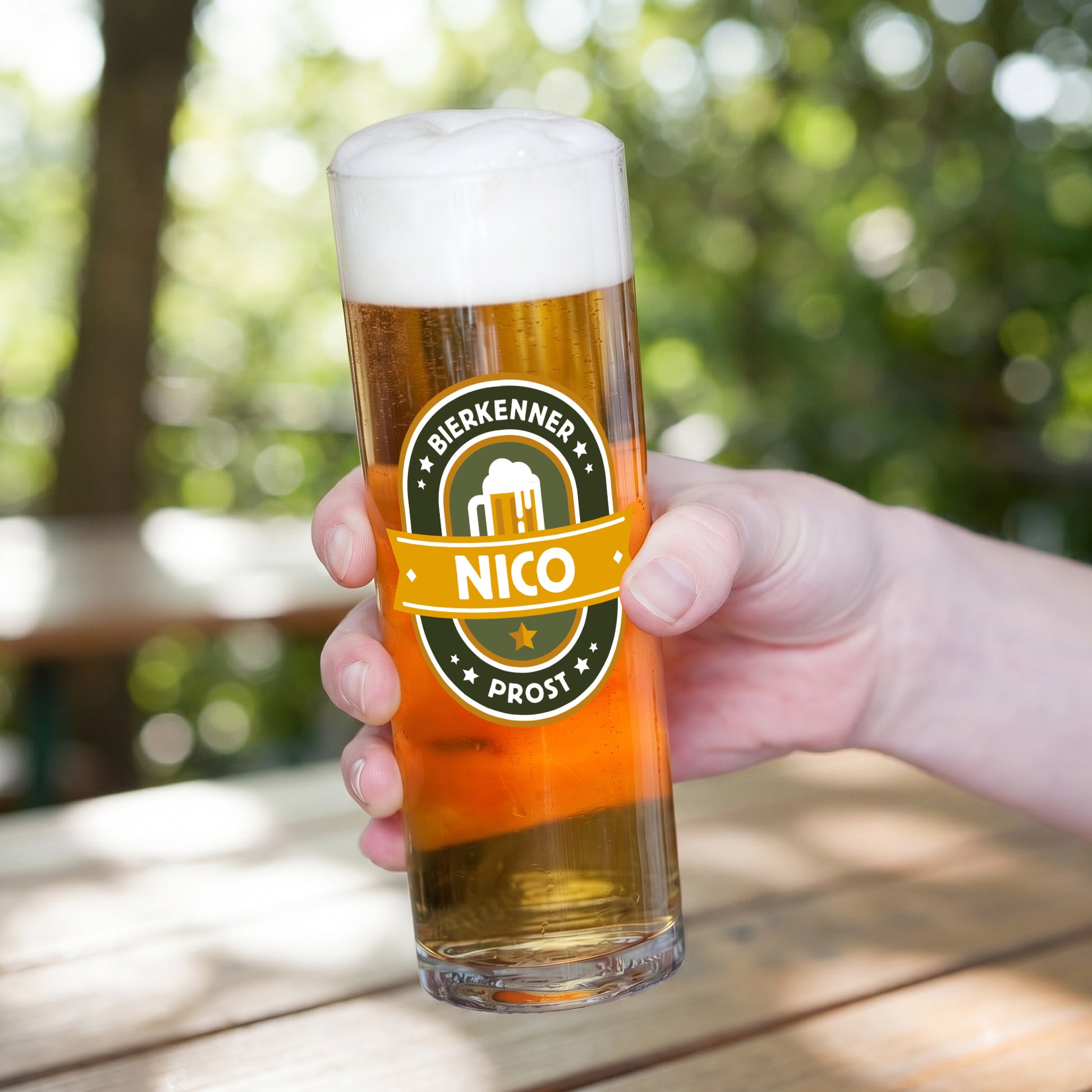 Personalisiertes Bierglas mit Name Nico und Bierkenner Prost Motiv, in der Hand gehalten auf Terrasse