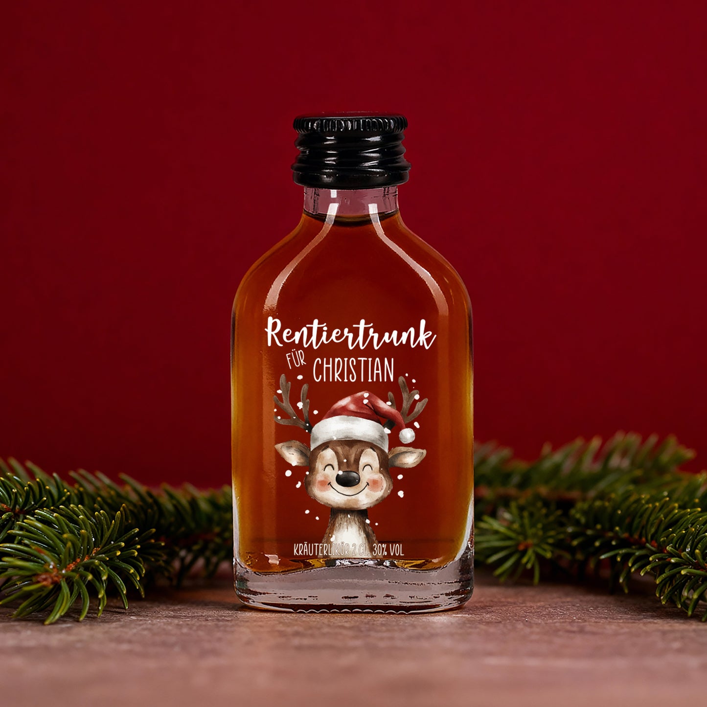 Kräuterlikör-Flasche „Rentiertrunk für Christian“ mit golden-brauner Farbe, festlicher roter Hintergrund und Tannenzweige im Vordergrund.