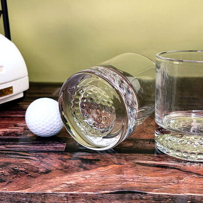 Zwei Gläser mit Golfstruktur liegend auf Holzboden neben dem Golfcart