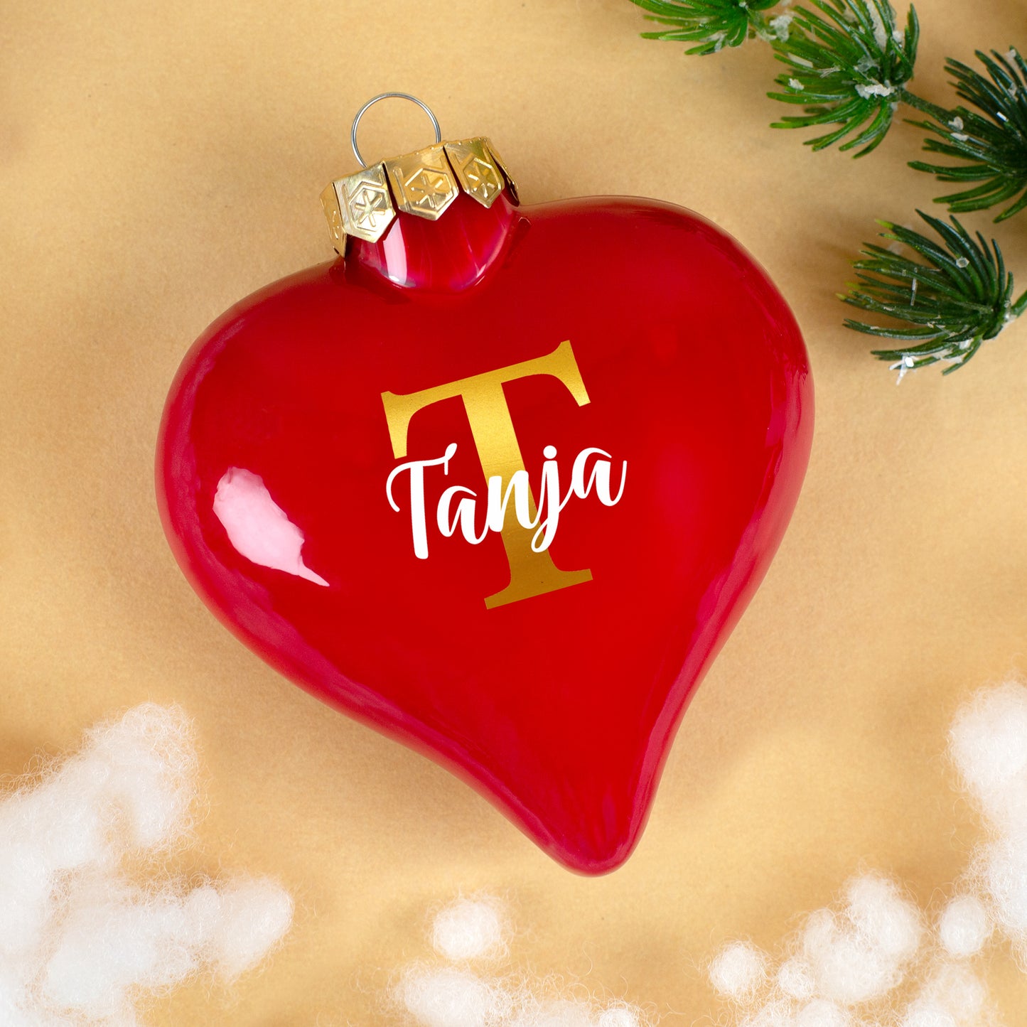 Rote Herz-Christbaumkugel mit goldener Initiale T und Name Tanja auf hellem Hintergrund