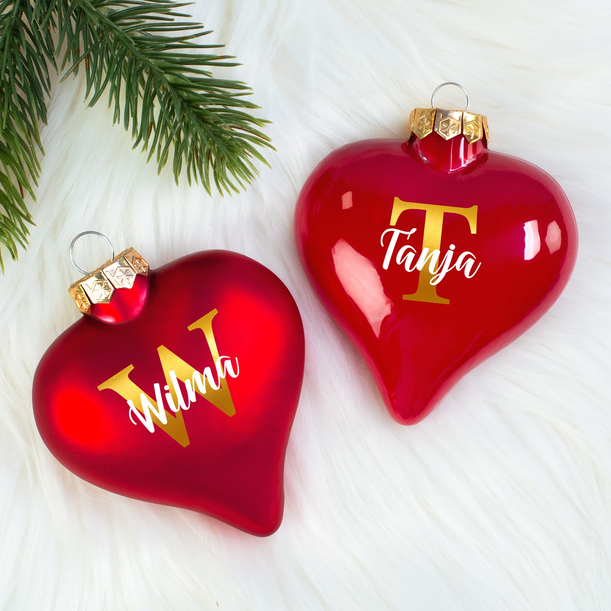 Zwei rote Herz-Christbaumkugeln mit goldenen Initialen W und T sowie Namen Wilma und Tanja nebeneinander