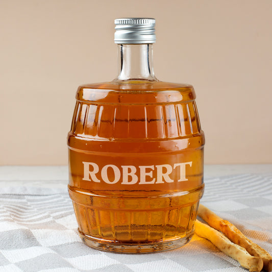 Glasflasche in Fassform mit Gravur ROBERT, befüllt mit Whisky, auf grauem Tuch