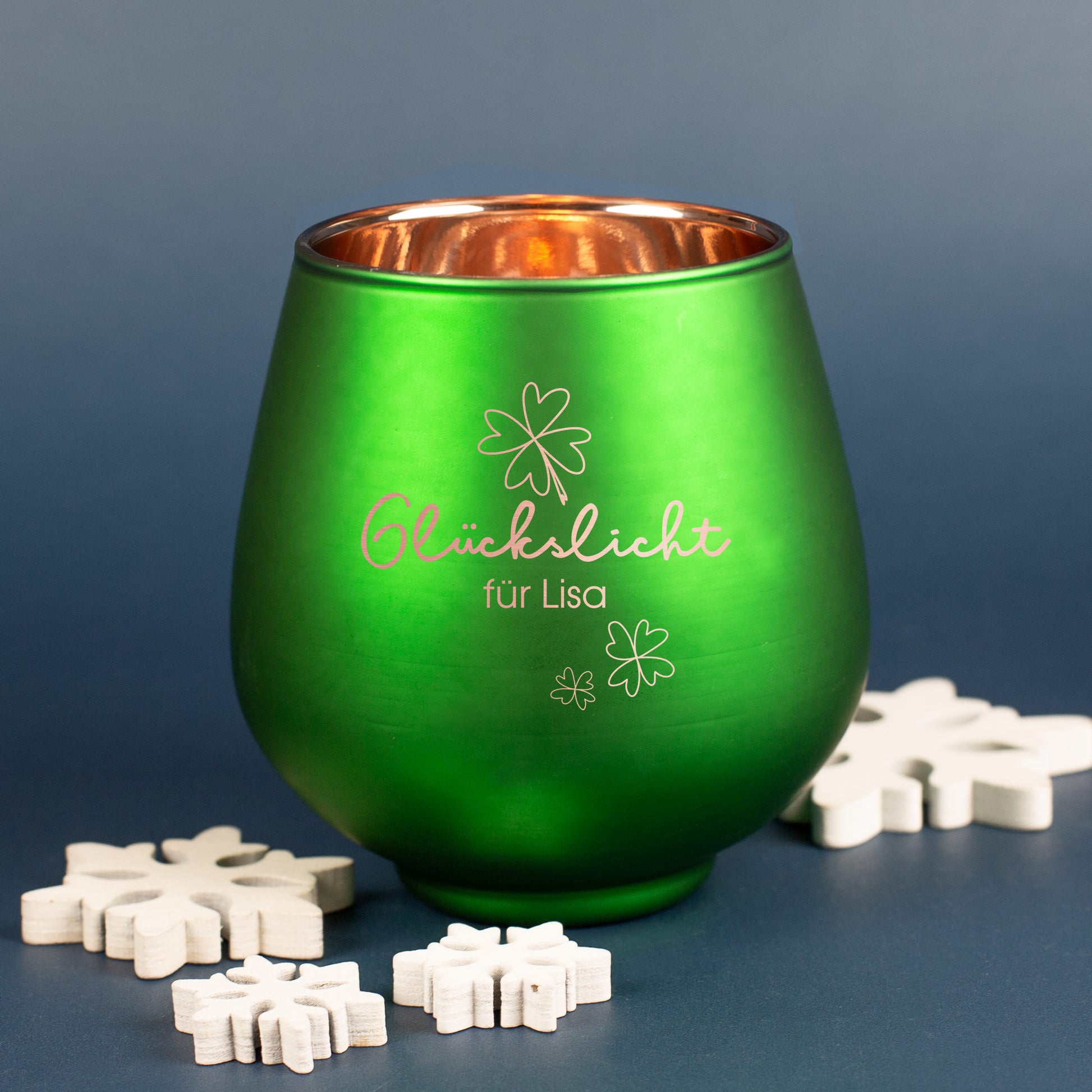 Grünes Windlicht mit Gravur „Glückslicht für Lisa“ und Kleeblättern, umgeben von weißen Deko-Schneeflocken