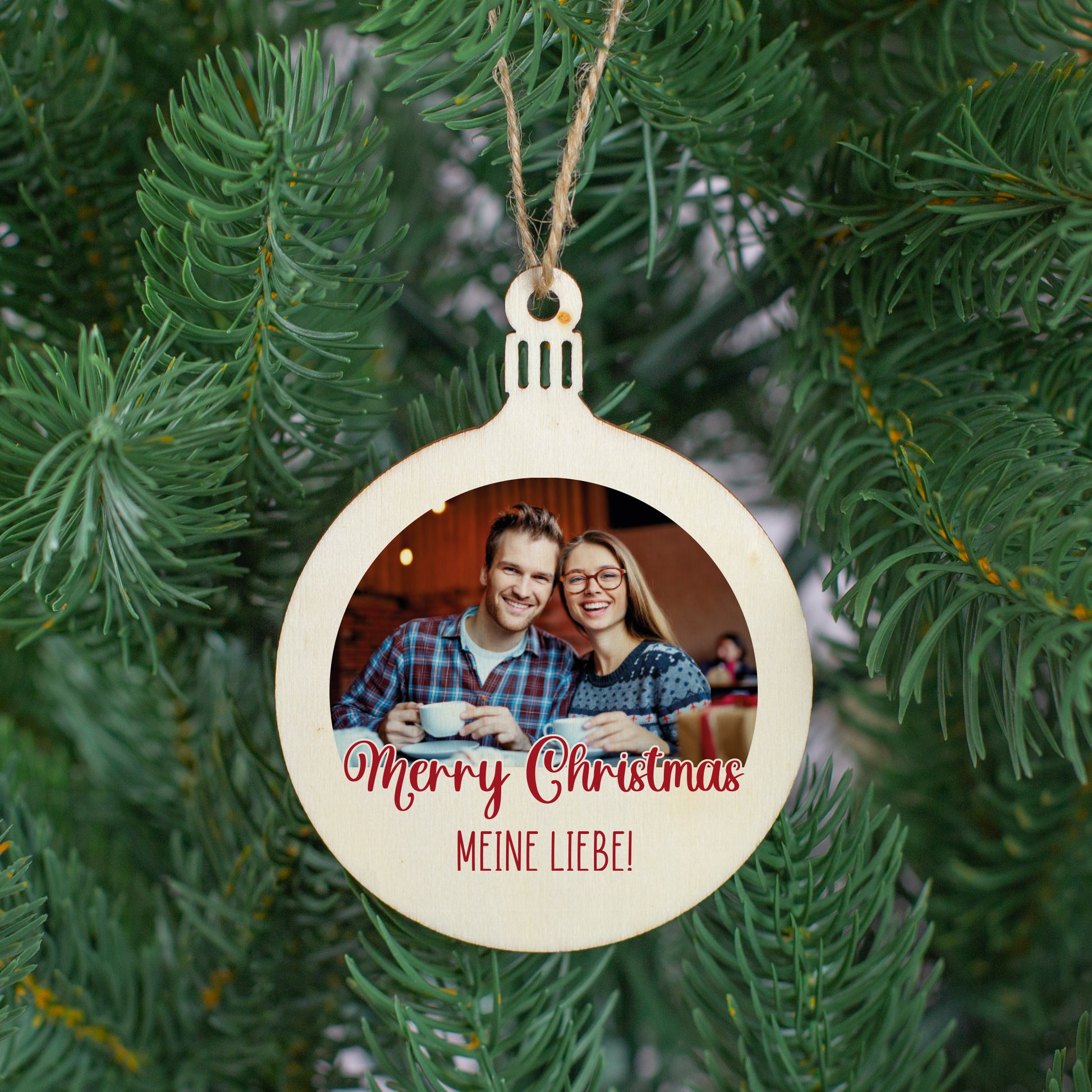 Personalisierter Christbaumanhänger mit Foto und Wunschtext – Holzanhänger „Merry Christmas“ mit roter Schrift, aufgehängt im Tannenbaum.