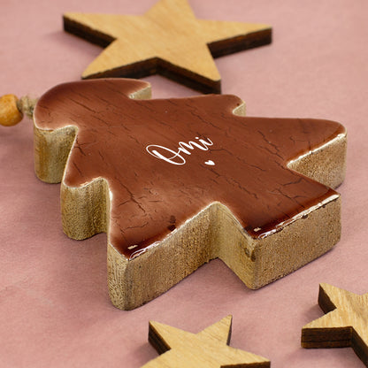 Personalisierter Holz-Tannenbaum mit Aufdruck Omi und Herz liegend zwischen dekorativen Holzsternen