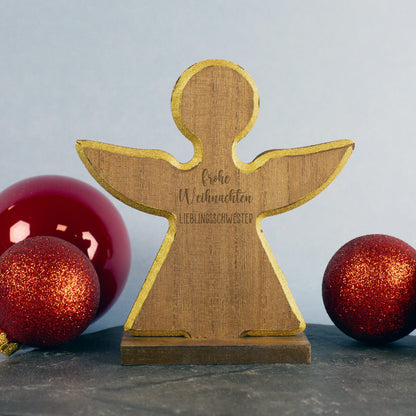 Holzengel mit Gravur Frohe Weihnachten Lieblingsschwester, goldene Kante, rote Weihnachtskugeln im Hintergrund