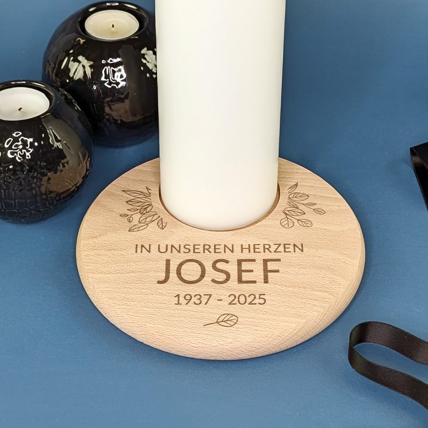 Detailaufnahme eines gravierten Holz-Kerzentellers zur Erinnerung mit weißer Kerze und Textgravur