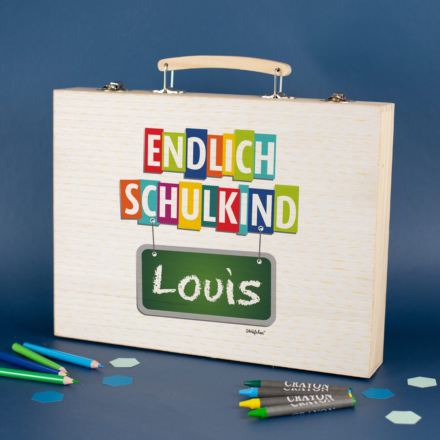 Personalisierter Malkoffer aus Holz mit „Endlich Schulkind“ Motiv und Name Louis vor blauem Hintergrund