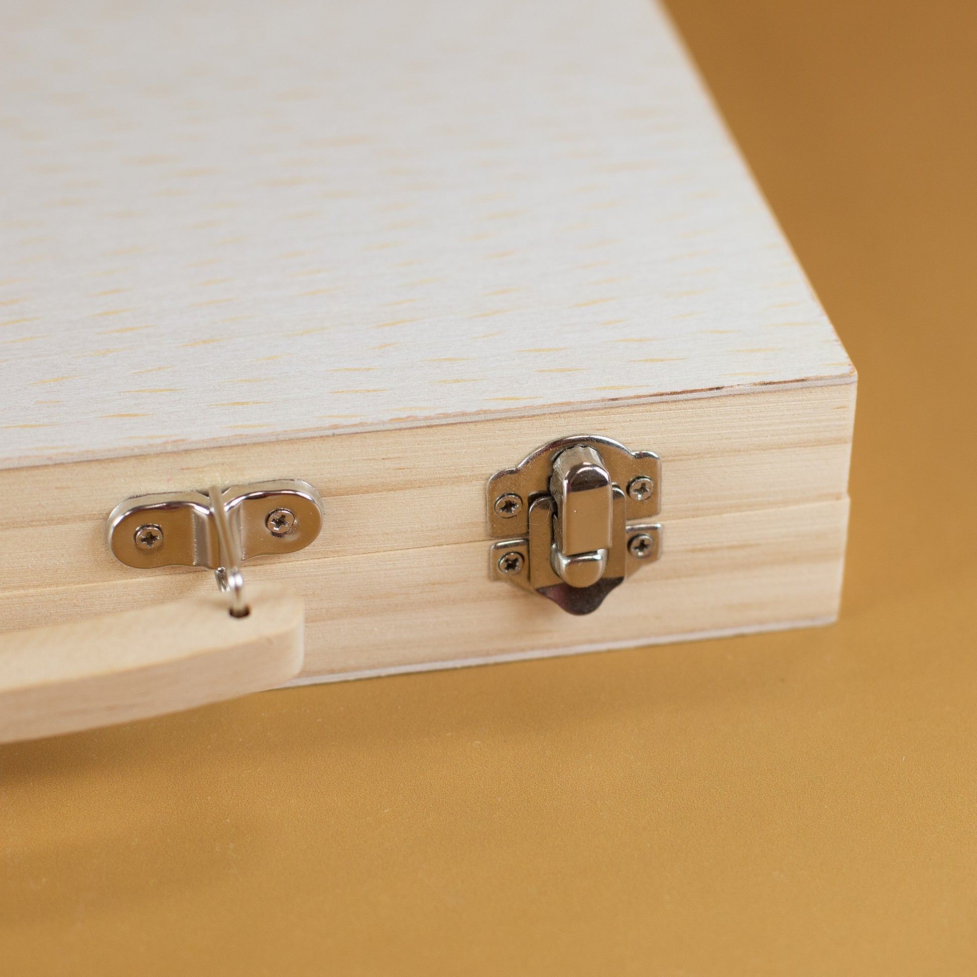 Nahaufnahme des Metallverschlusses am hellen Holzkoffer für Kinder