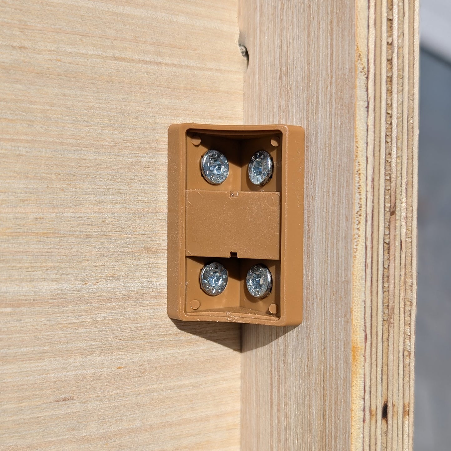 Nahaufnahme eines braunen Magnetverschlusses mit vier Schrauben an der Innenseite der Holzbank zur stabilen Fixierung