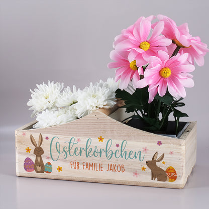 Osterkörbchen aus Holz mit Hasenmotiv und Wunschtext, bepflanzt mit Frühlingsblumen als Osterdekoration
