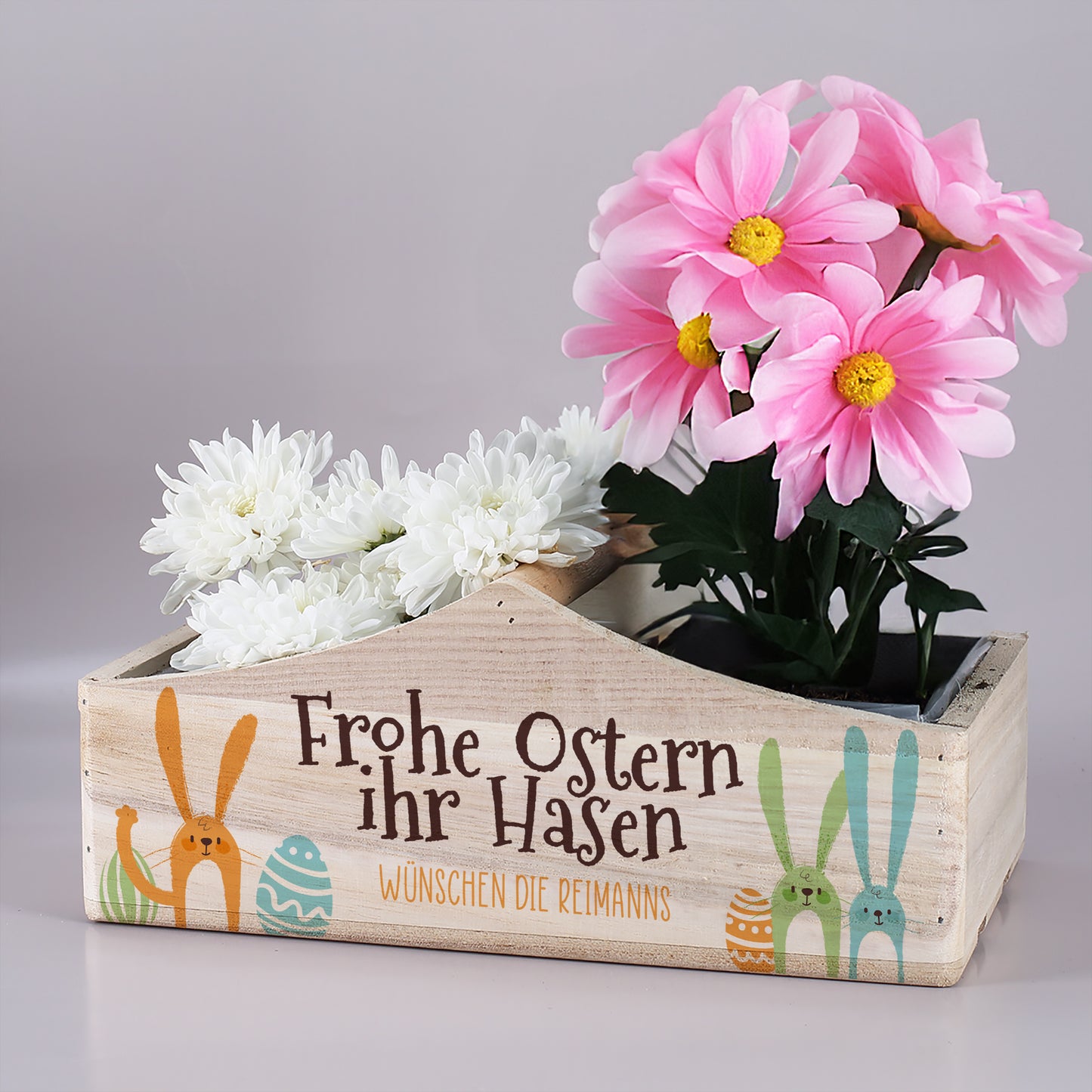 Personalisierter Pflanzkorb mit Mittelgriff und Ostermotiv „Frohe Ostern ihr Hasen“ befüllt mit Blumen