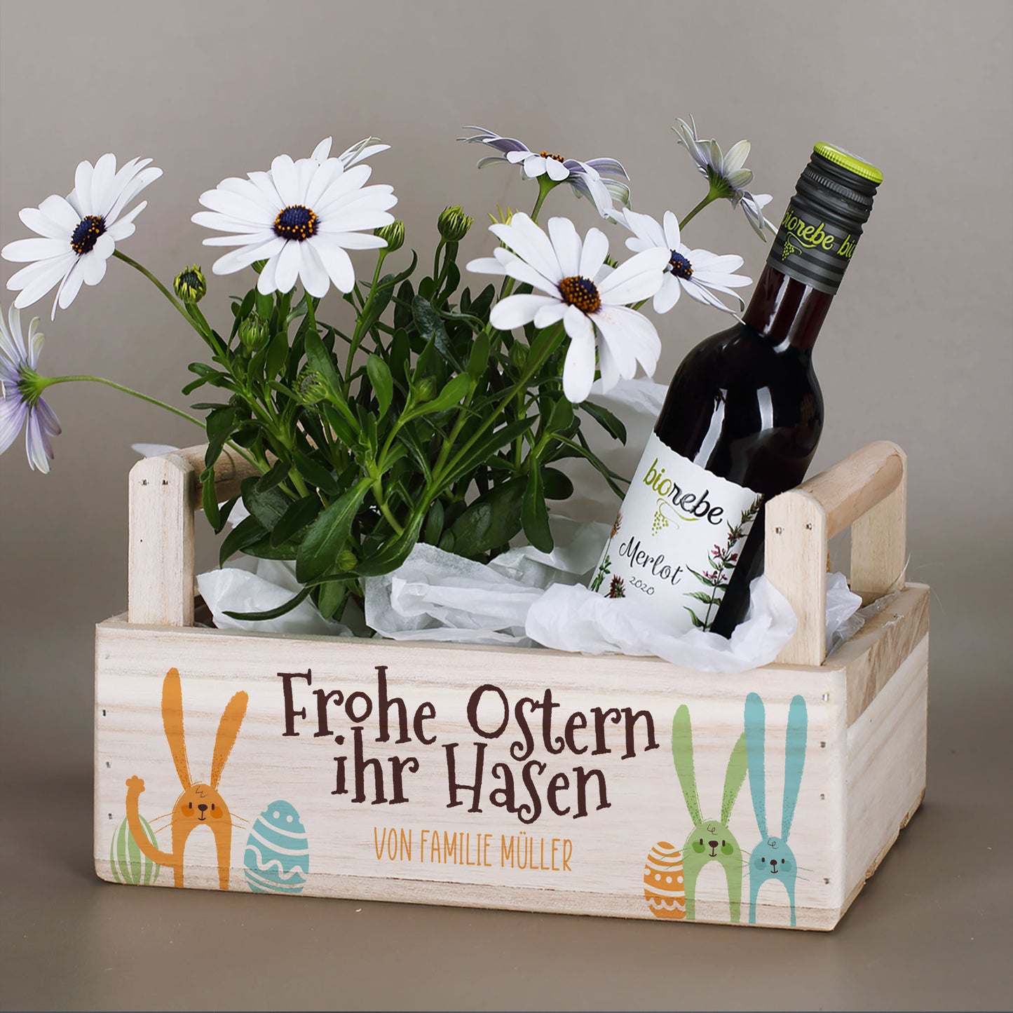 Pflanzkorb mit zwei seitlichen Griffen und Ostermotiv „Frohe Ostern ihr Hasen“ bepflanzt mit Blumen