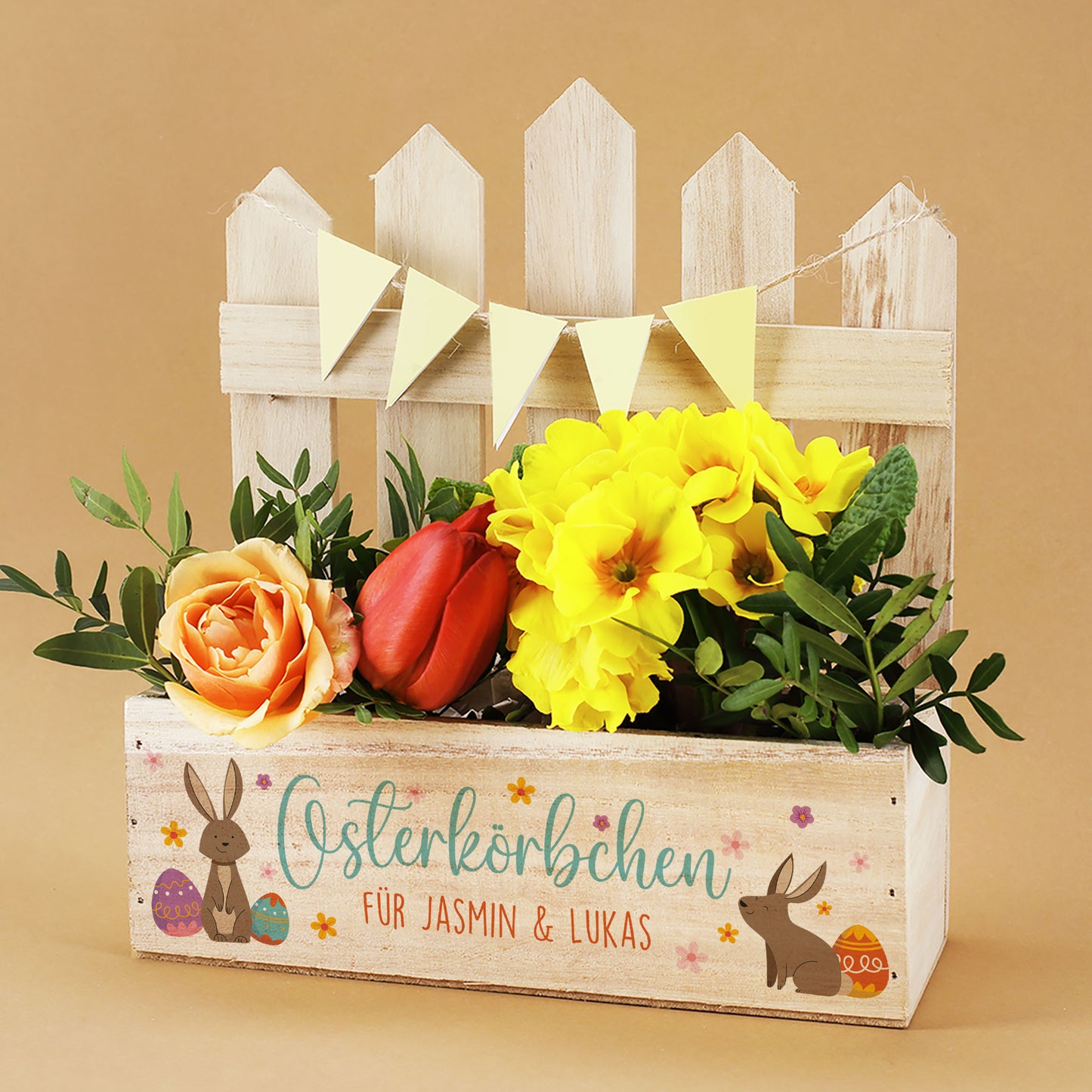 Personalisierter Pflanzkorb aus Holz zu Ostern mit Zaun, Hasenmotiv und Aufdruck „Osterkörbchen“ mit Blumen dekoriert