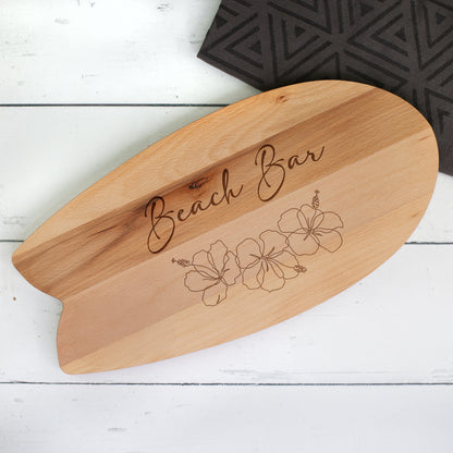 Servierbrett in Surfbrett-Form aus Holz mit Gravur „Beach Bar“ und Hibiskusblüten im Hawaii-Stil