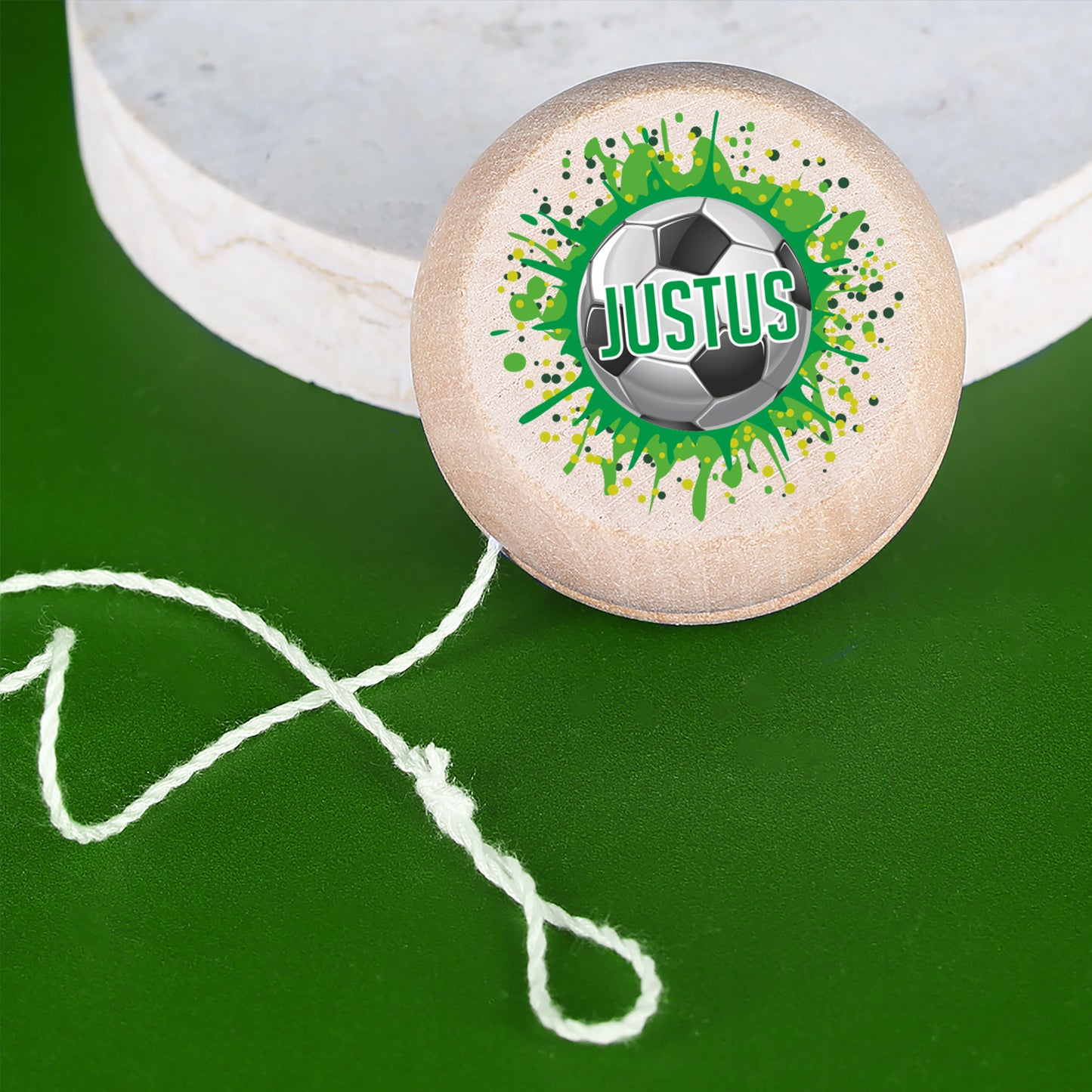 Holz-Yo-Yo mit Fußball und Name Justus auf grünem Hintergrund