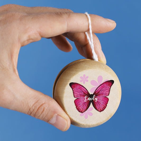 Yo-Yo mit pinkem Schmetterlingsmotiv und Name Emily in Kinderhand vor blauem Hintergrund