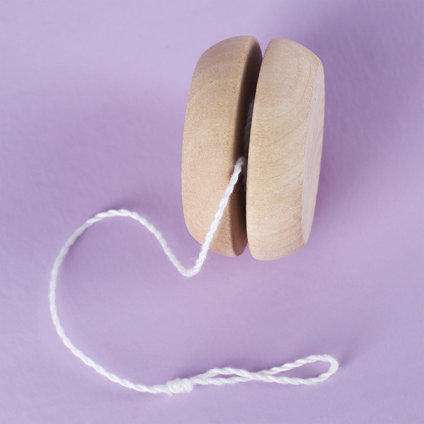 Seitenansicht des Holz-Yo-Yos mit Schnur auf lila Hintergrund